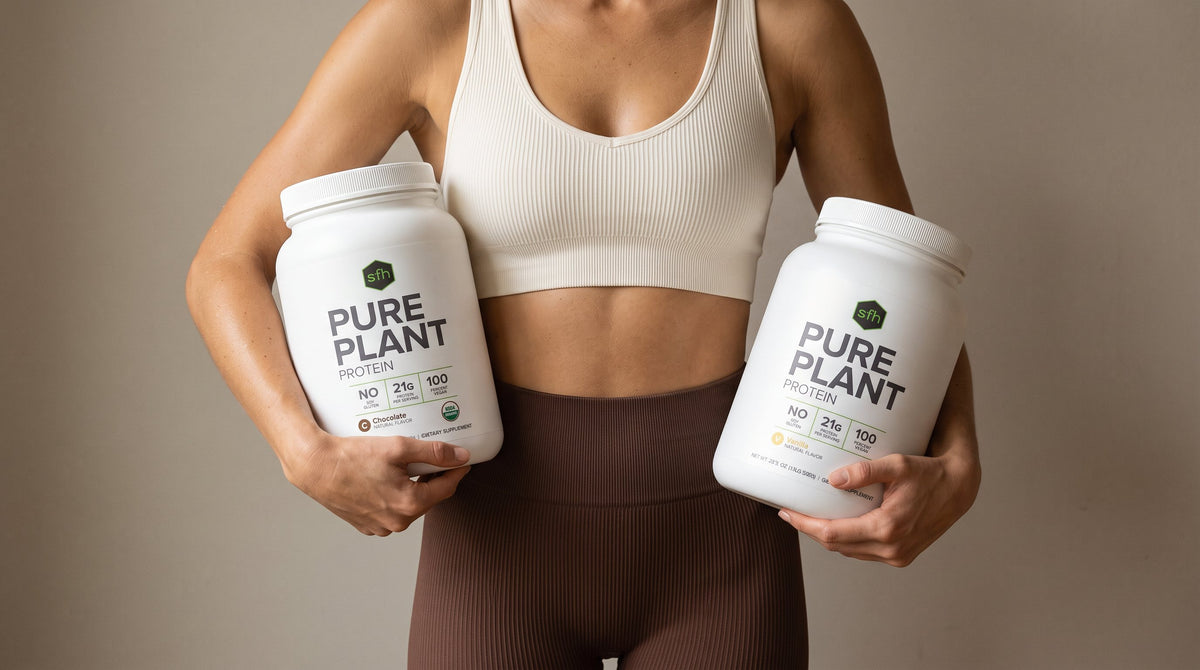 Woman in workout clothes holding a tub of PURE PLANT under each arm, chocolate and vanilla